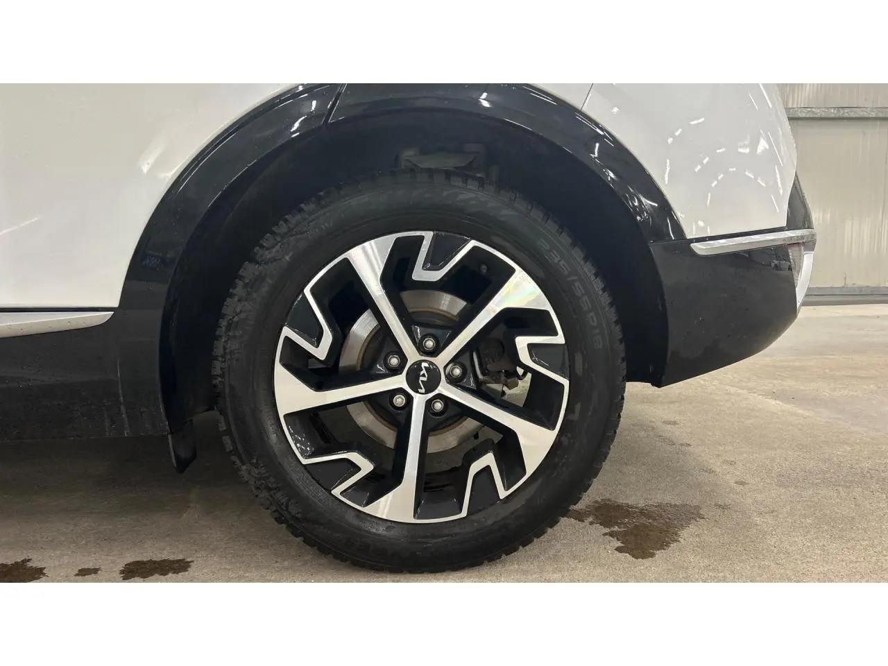 Gros plan sur la roue arrière droite du KIA SPORTAGE blanc avec jante alliage 18 pouces noir et argent.