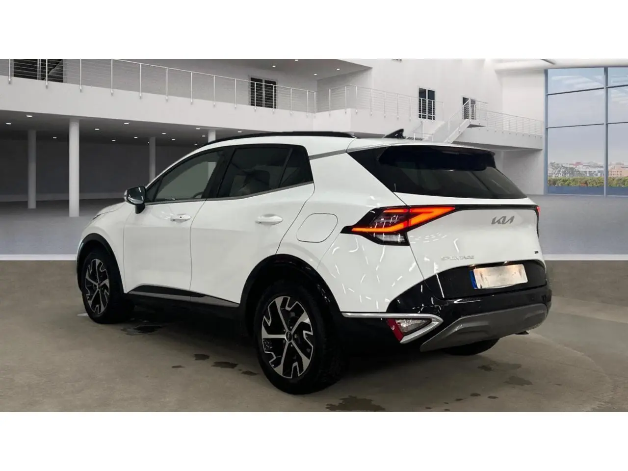 KIA SPORTAGE hybride blanc vue 3/4 arrière droit avec toit noir et jantes alliage 18 pouces en intérieur showroom.