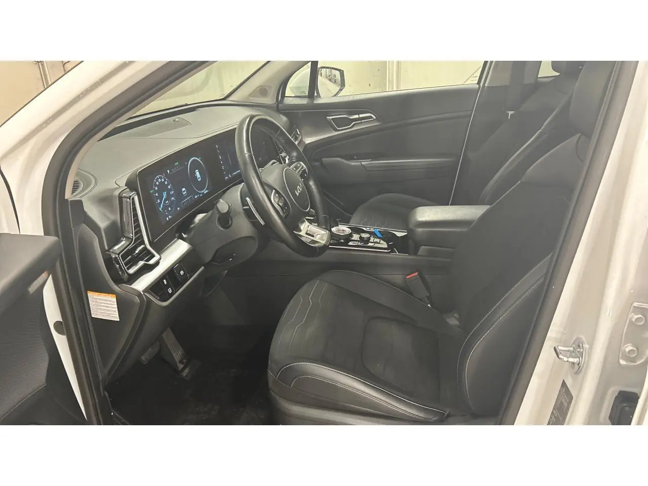 Intérieur avant droit du KIA SPORTAGE blanc 2022, volant cuir GT-line et tableau de bord digital lumineux.