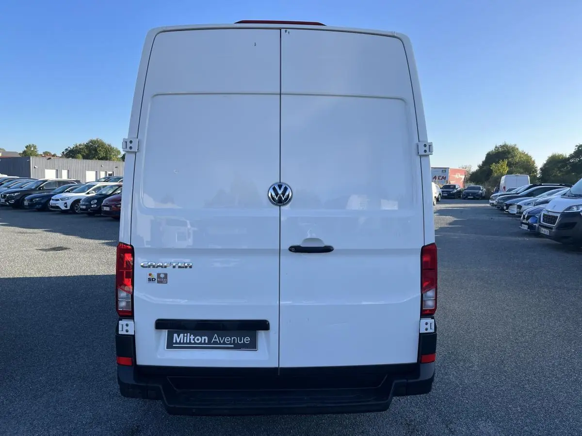 Vue arrière d'un utilitaire Volkswagen Crafter blanc avec portes battantes et logo central visible.