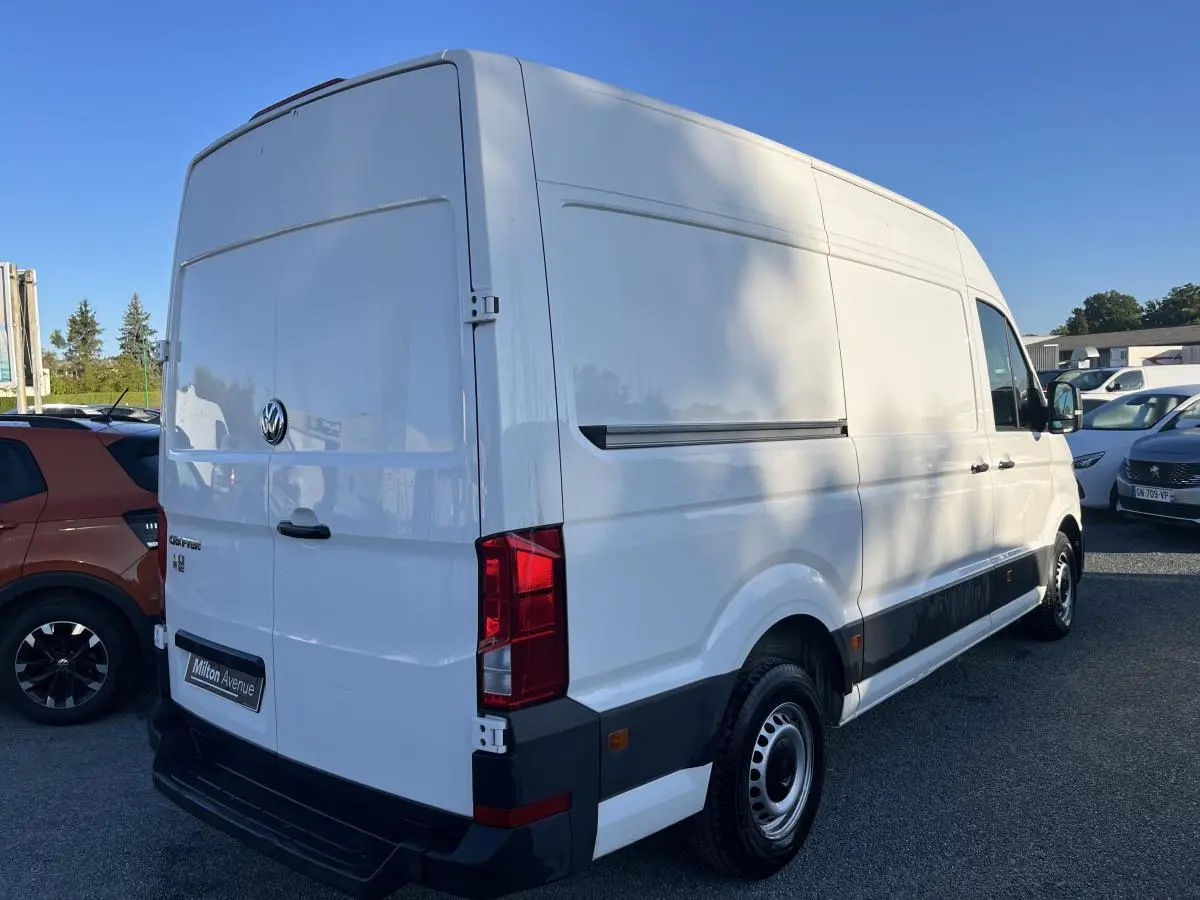 Volkswagen Crafter fourgon blanc vu en 3/4 arrière droit, portes battantes arrière fermées et jantes acier argentées.