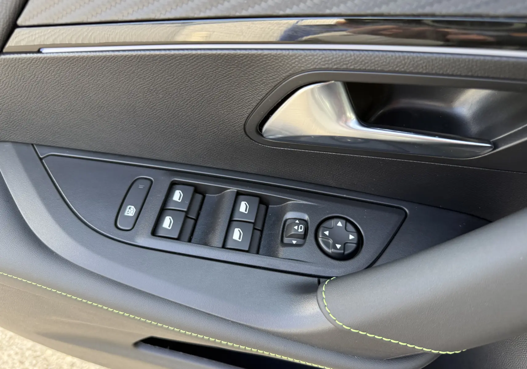Gros plan sur la commande des vitres et rétroviseurs côté gauche intérieur du Peugeot 2008 Hybrid gris selenium toit noir.
