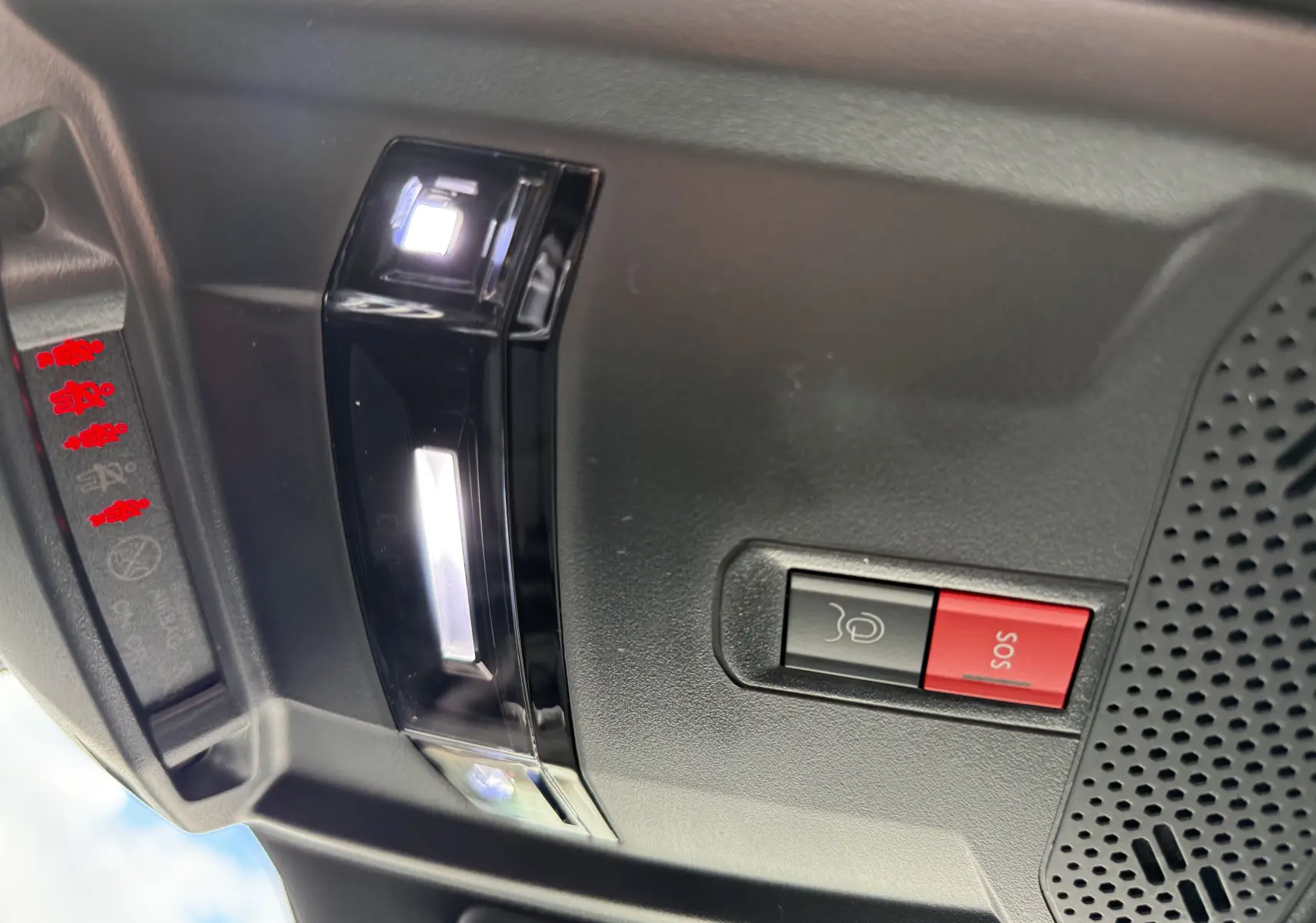 Gros plan sur la console de toit intérieure du Peugeot 2008 Hybrid 145ch GT, avec bouton SOS rouge et éclairage LED blanc.