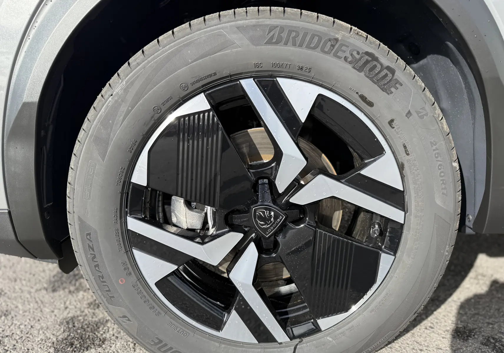 Gros plan sur la jante noire et argentée du Peugeot 2008 Hybrid 145ch GT avec pneu Bridgestone Turanza.