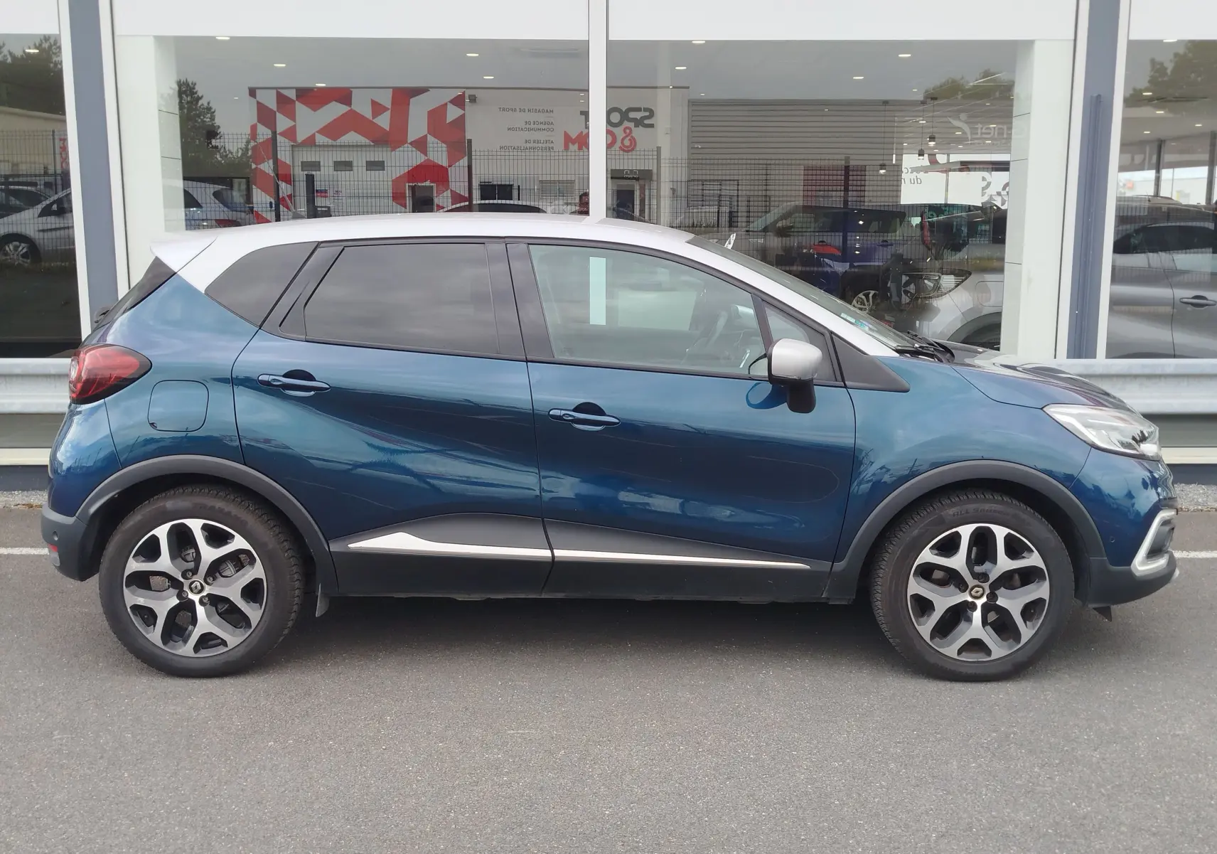Profil côté gauche d'un Renault Captur 2018 bleu marine fumé avec toit gris platine et jantes alliage bi-ton.