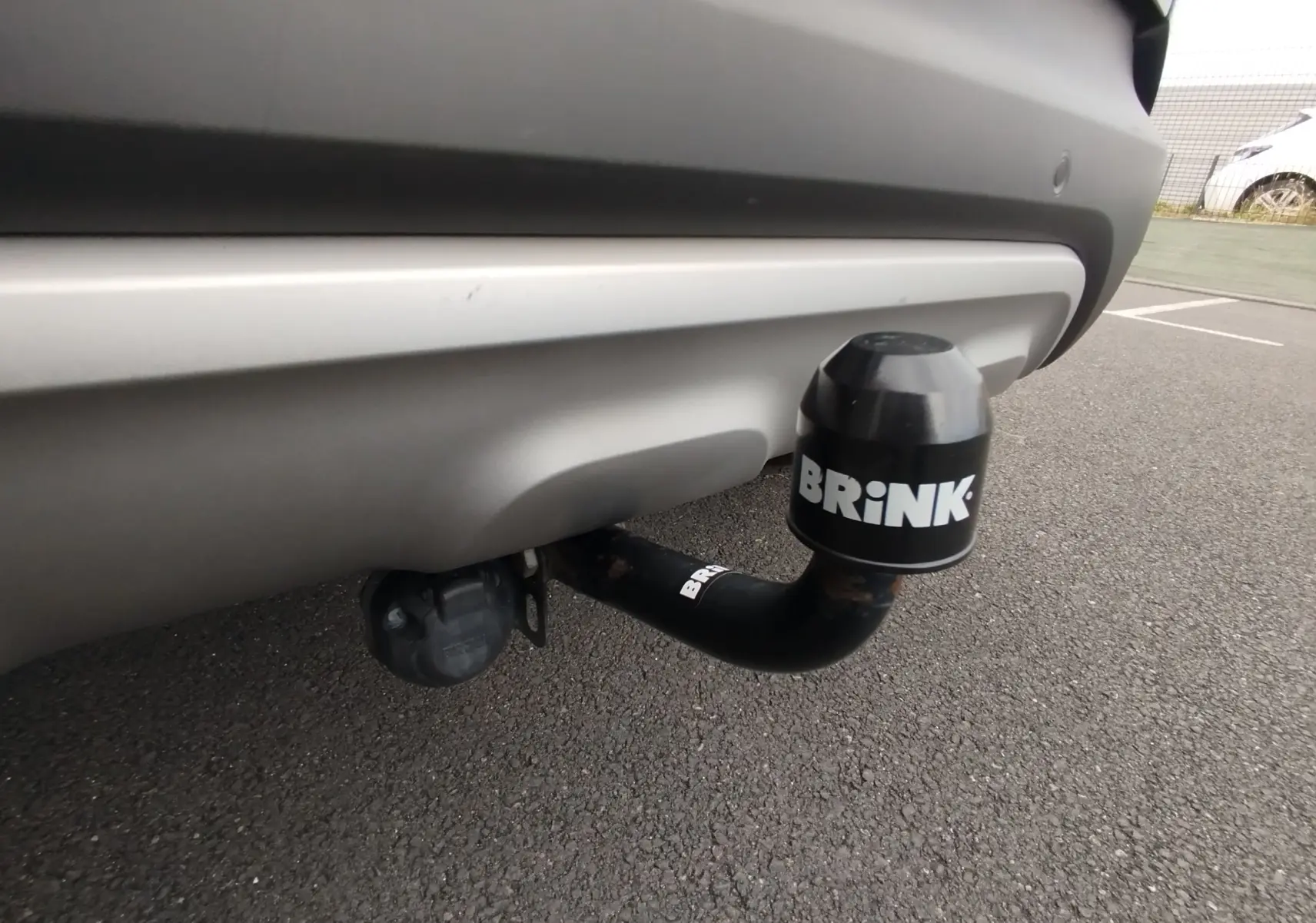 Gros plan sur l'attelage de remorque noir Brink sous le pare-chocs arrière gris platine du Renault Captur 2018.