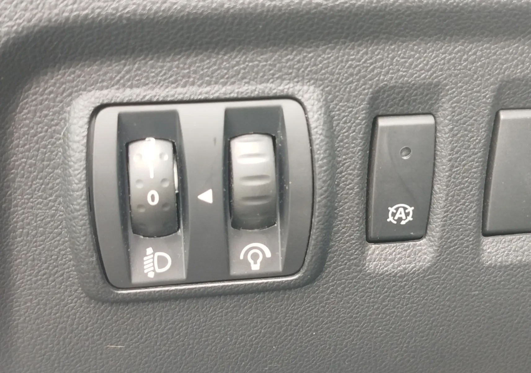 Gros plan sur les commandes de réglage des phares et de l'éclairage intérieur du Renault Captur bleu marine fumé 2018.