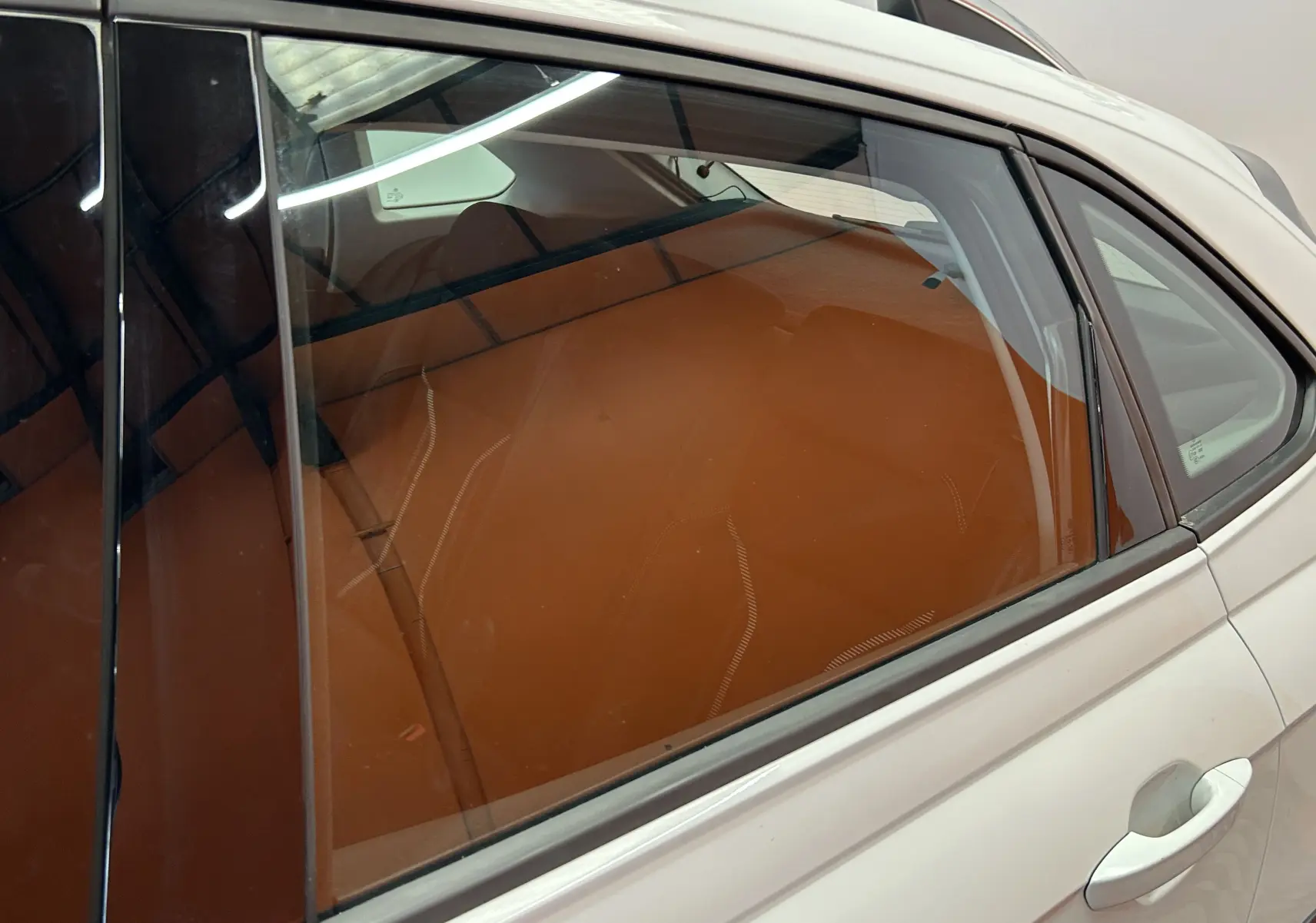 Vue latérale droite du Volkswagen Taigo blanc pur 2022, mettant en valeur les sièges arrière en cuir brun visible à travers la vitre.