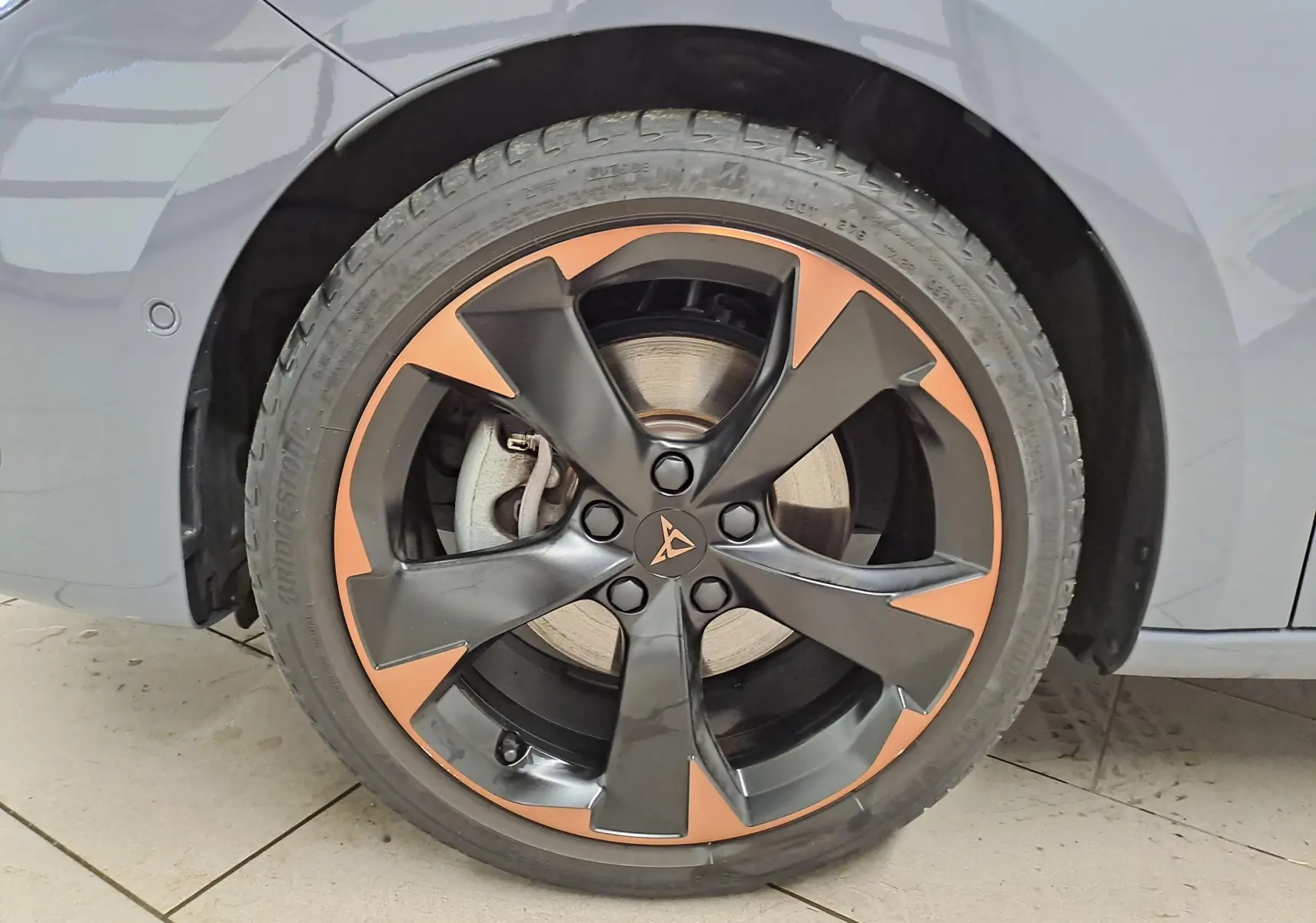 Gros plan sur la jante alliage 18'' cuivrée et noire du côté arrière droit de la CUPRA Leon ST gris Graphène.