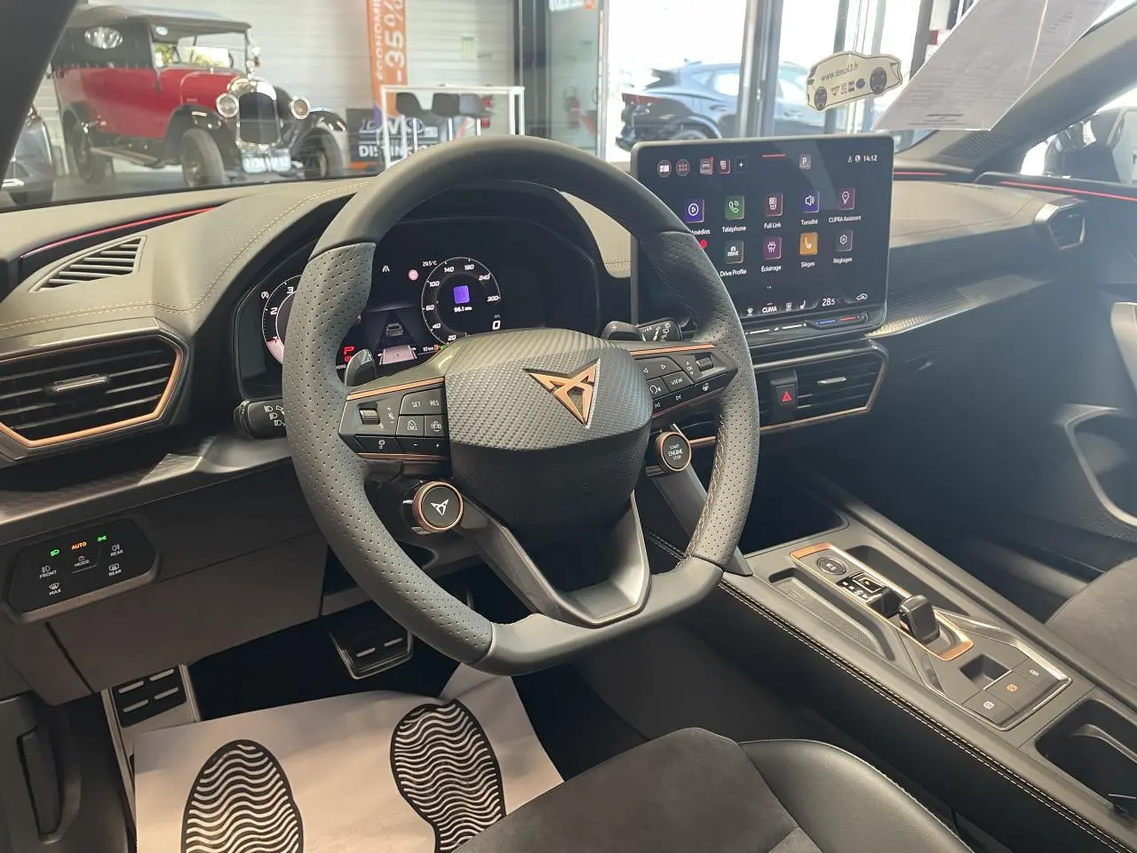 Vue intérieure du poste de conduite de la CUPRA Leon gris, volant perforé avec logo cuivré et écran tactile HD.