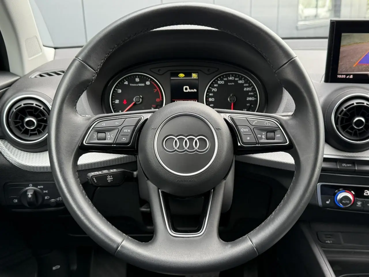 Vue rapprochée du volant noir de l'Audi Q2 35 TFSI 150 S-Tronic S-Line avec commandes intégrées et tableau de bord digital.