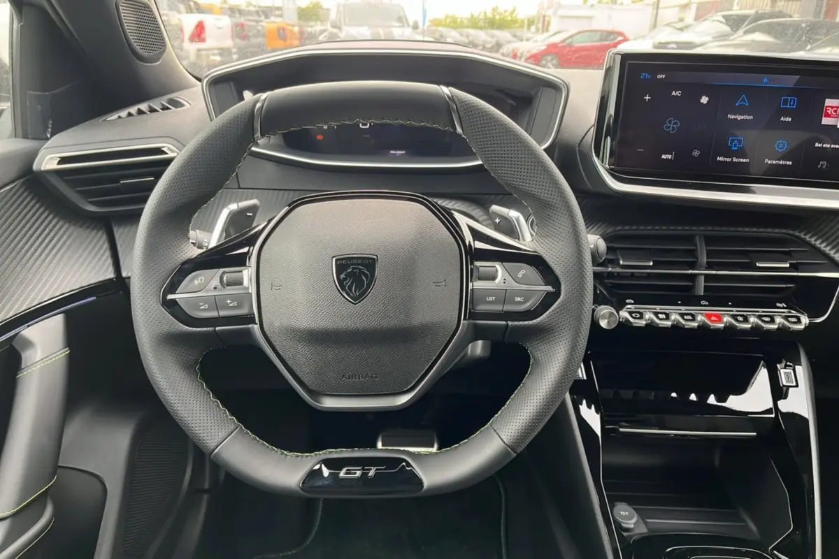 Vue intérieure centrée sur le volant GT du Peugeot 2008 Hybrid 145, avec tableau de bord numérique et écran tactile.