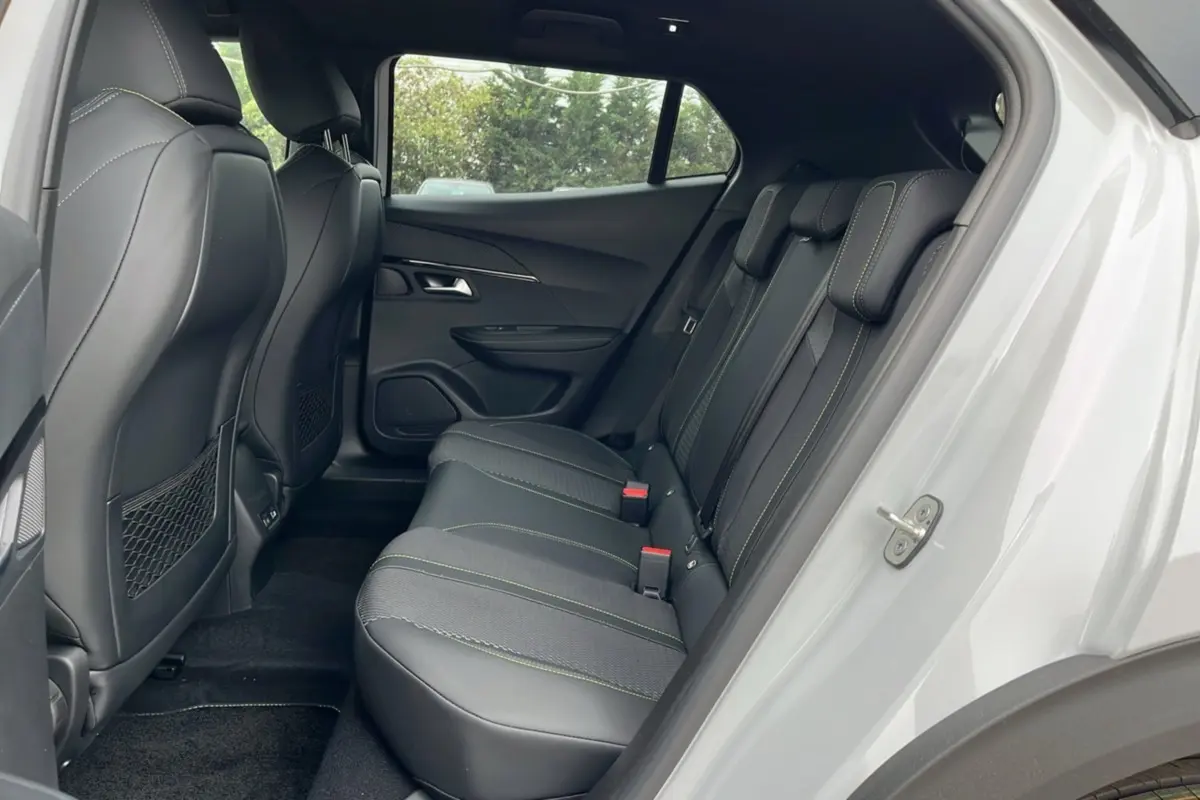 Vue intérieure côté droit des sièges arrière en cuir noir avec surpiqûres vertes du Peugeot 2008 Hybrid 145 GT Vision 2025 blanc okénite.