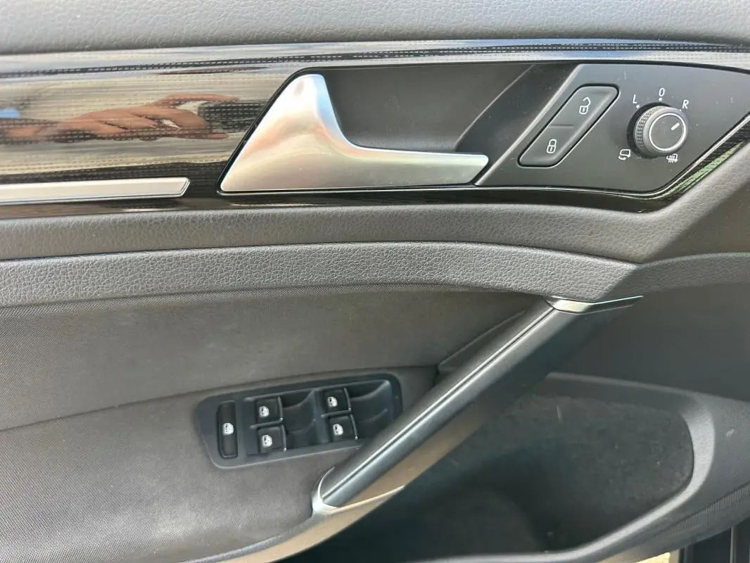 Vue rapprochée de la porte côté gauche de la Volkswagen Golf noire, avec commandes électriques et poignée argentée.