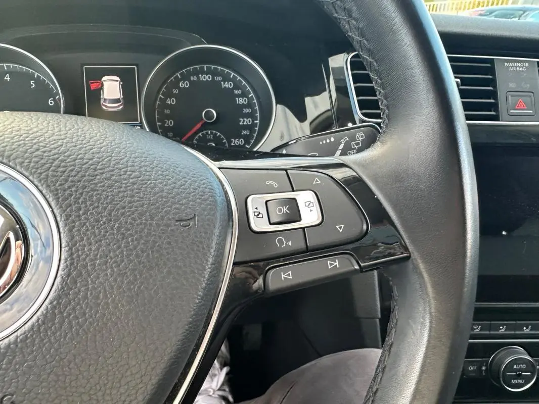 Gros plan sur le volant multifonctions noir de la Volkswagen Golf 2018, avec commandes intégrées et tableau de bord en arrière-plan.