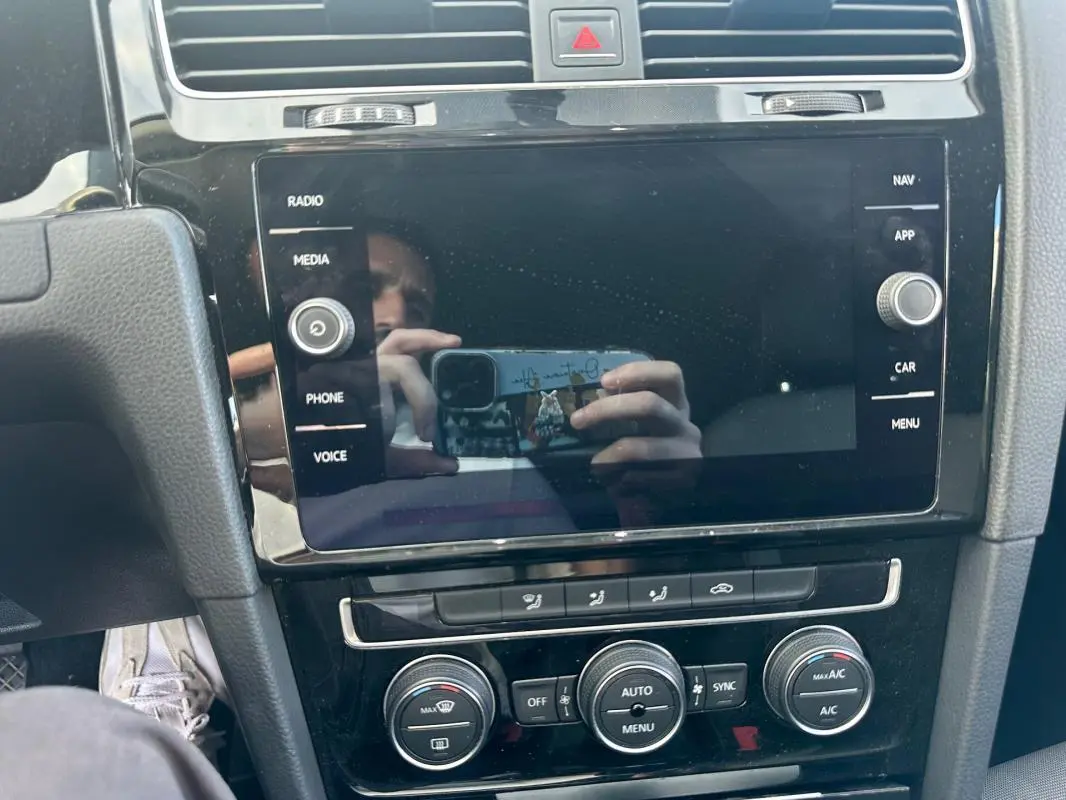 Vue rapprochée du tableau de bord noir de la Volkswagen Golf 1.5 TSI 2018 avec écran tactile et commandes climatisation.