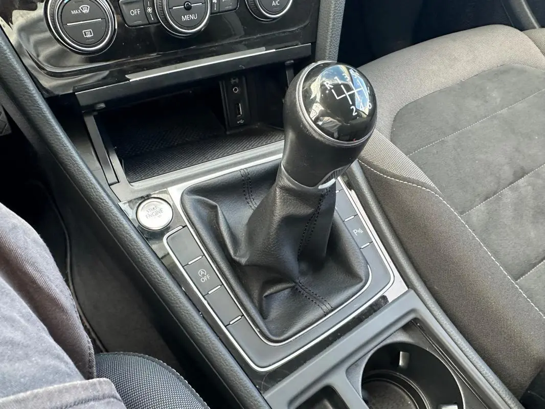 Gros plan sur la commande de boîte manuelle noire et la console centrale de la Volkswagen Golf 2018, sièges gris.