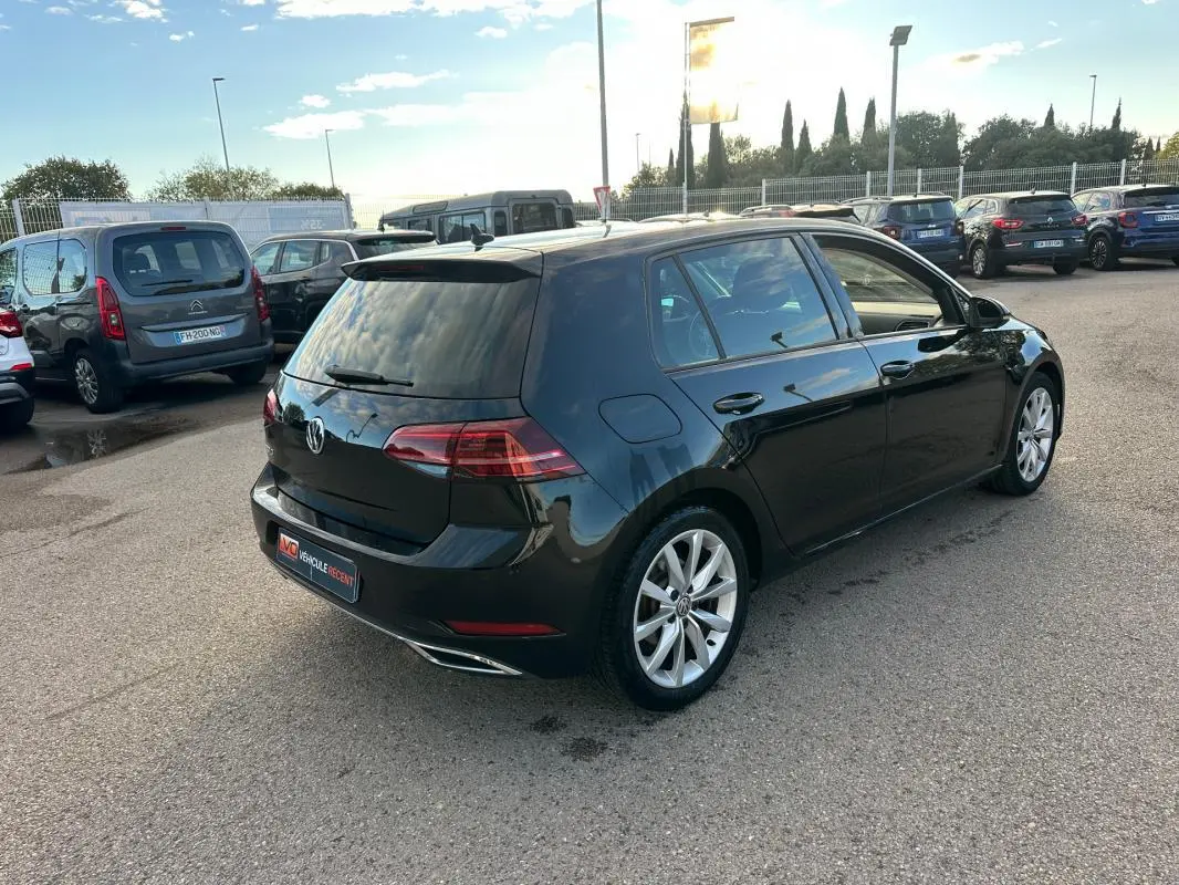 Volkswagen Golf noire vue en 3/4 arrière droit, avec jantes alliage 17 pouces et vitres teintées.