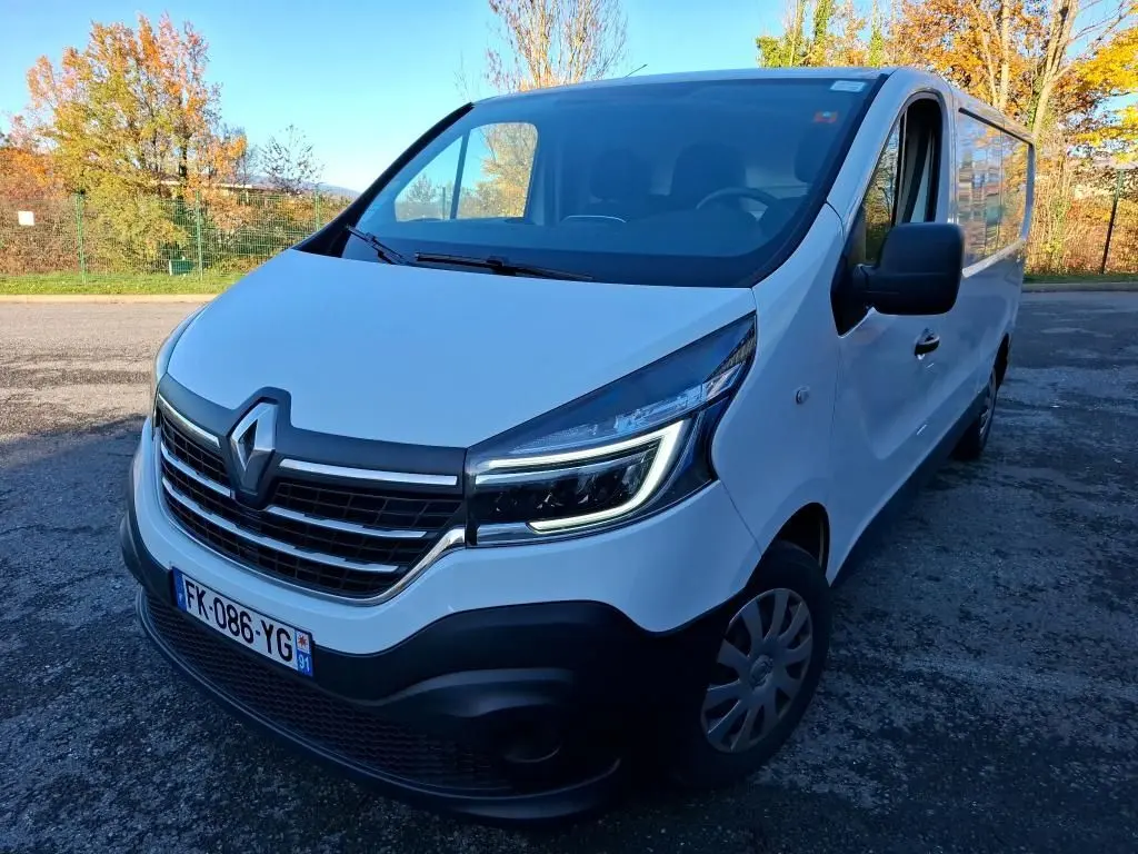 Renault Trafic Fourgon blanc vu en 3/4 avant droit, avec calandre noire et phares LED allumés.