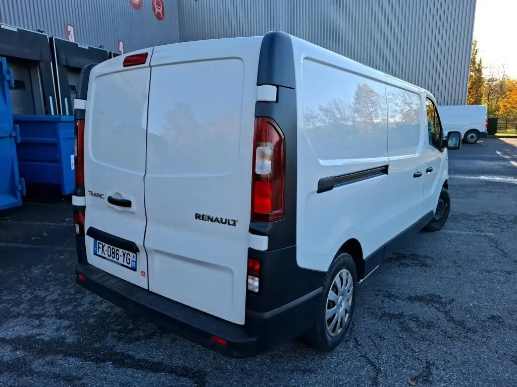 Renault Trafic blanc vu en 3/4 arrière droit, fourgon utilitaire avec portes arrière fermées et jantes acier.
