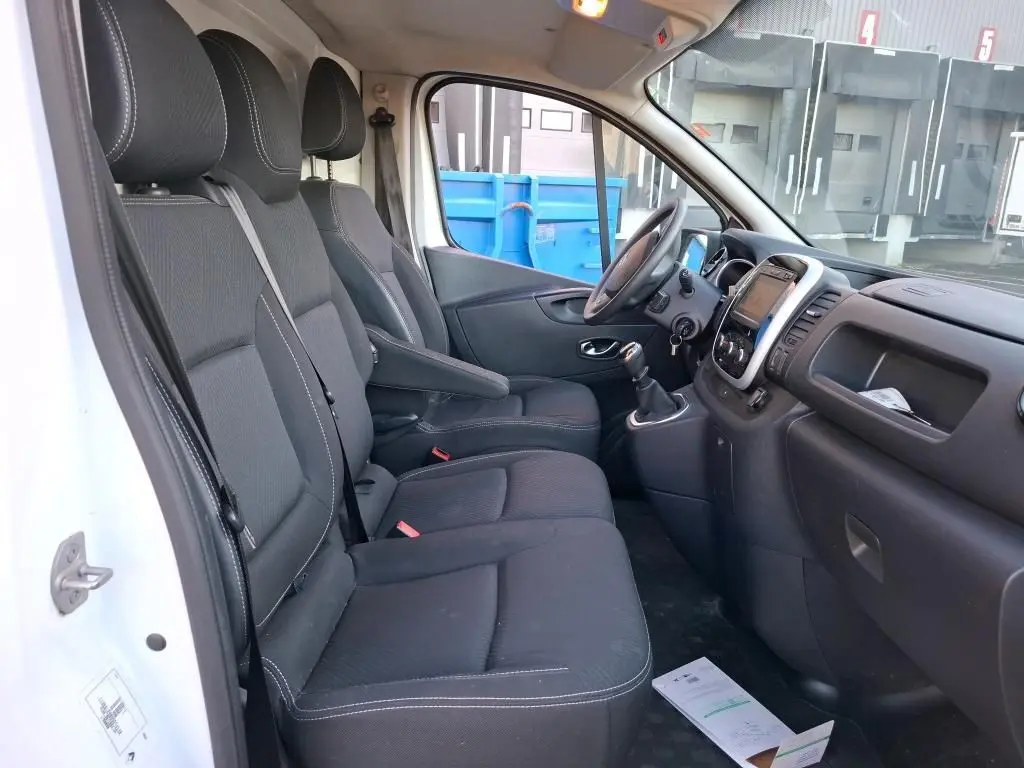 Intérieur du Renault Trafic Fourgon blanc 2019 vu côté conducteur, montrant sièges noirs et tableau de bord avec GPS intégré.