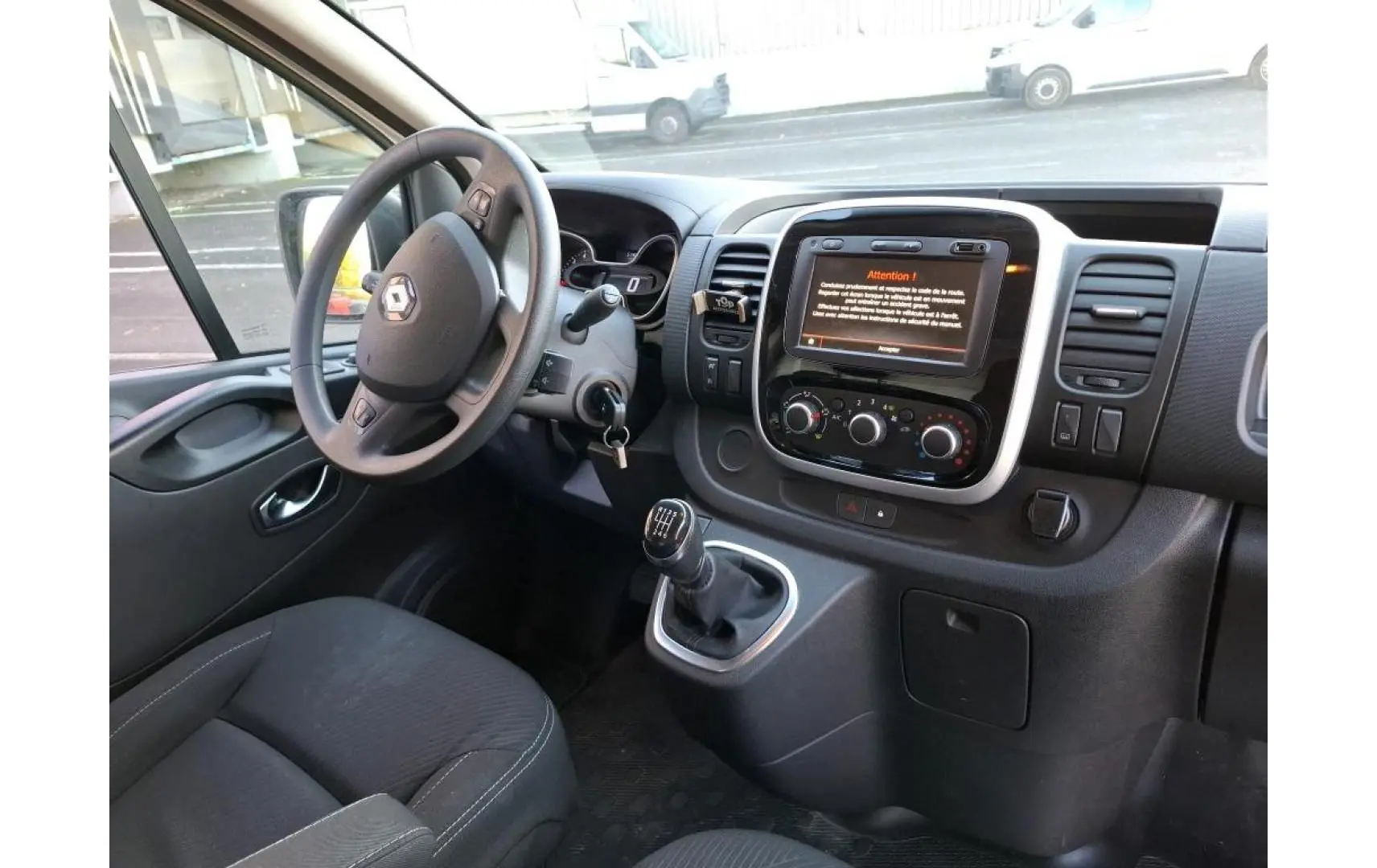 Vue intérieure côté conducteur du Renault Trafic Fourgon 2019, montrant le volant, levier de vitesses manuel et écran tactile central.