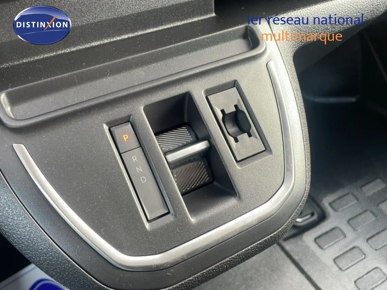 Gros plan sur la console centrale noire du Citroën Jumpy gris titane, avec levier de vitesses automatique et commandes intégrées.