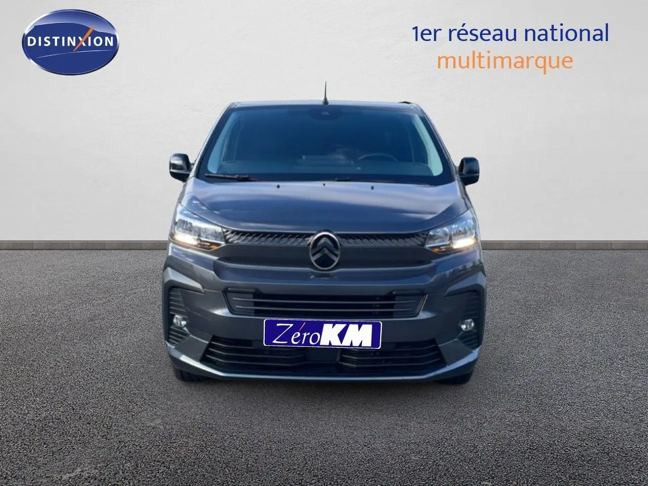 Vue frontale d'un Citroën Jumpy Van Long L3 gris titane métal avec phares allumés sur fond neutre.