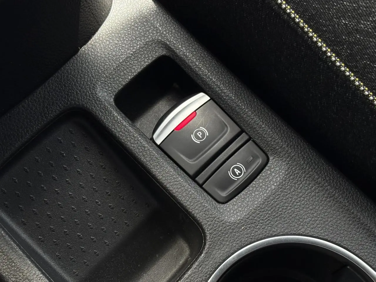 Gros plan sur la console centrale noire du Renault Captur 2025, montrant le frein de parking électrique et l'auto-hold.