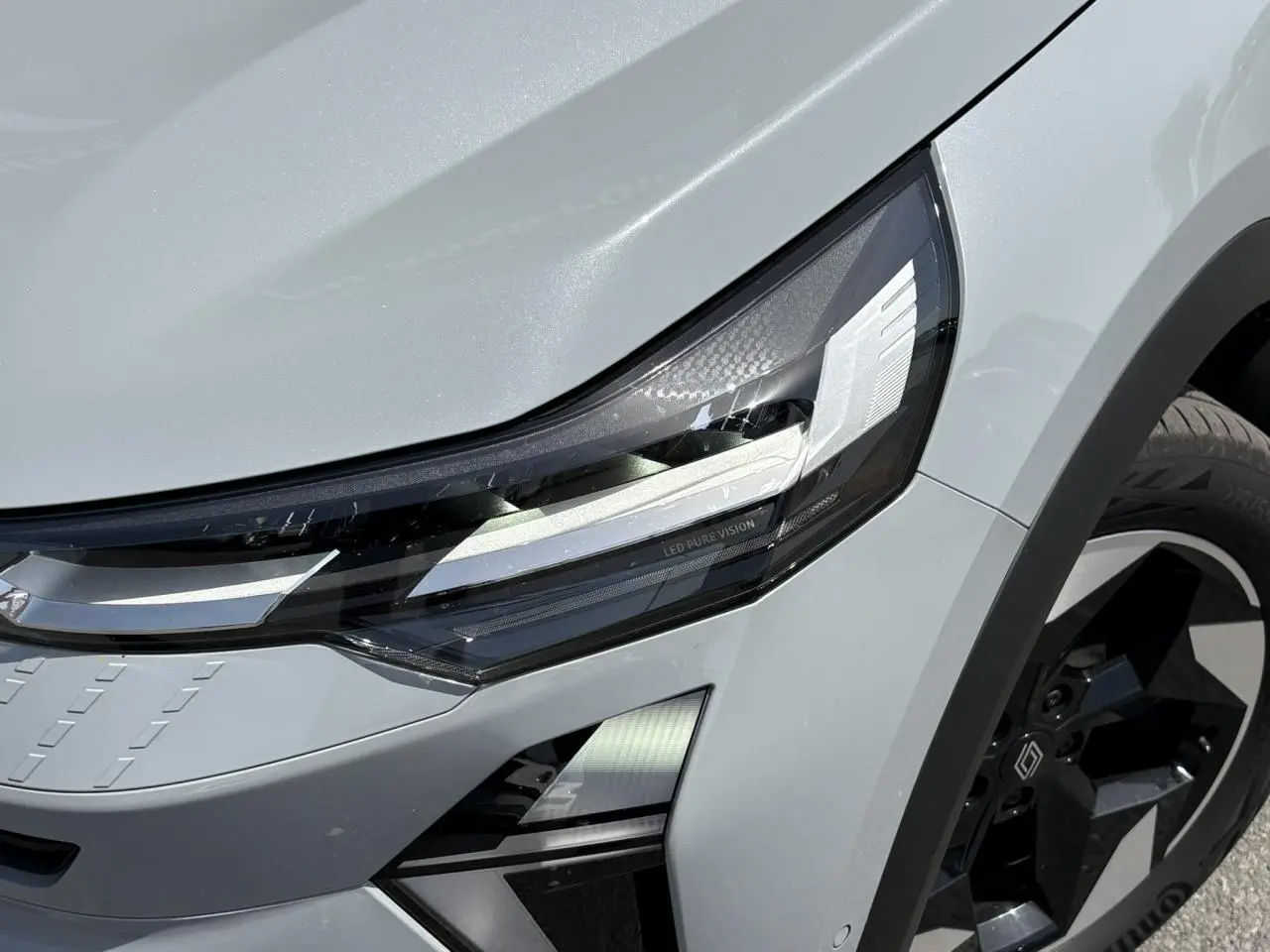 Gros plan sur le phare avant gauche et la roue noire du Renault Captur Gris Rafale 2025, détail LED Pure Vision.