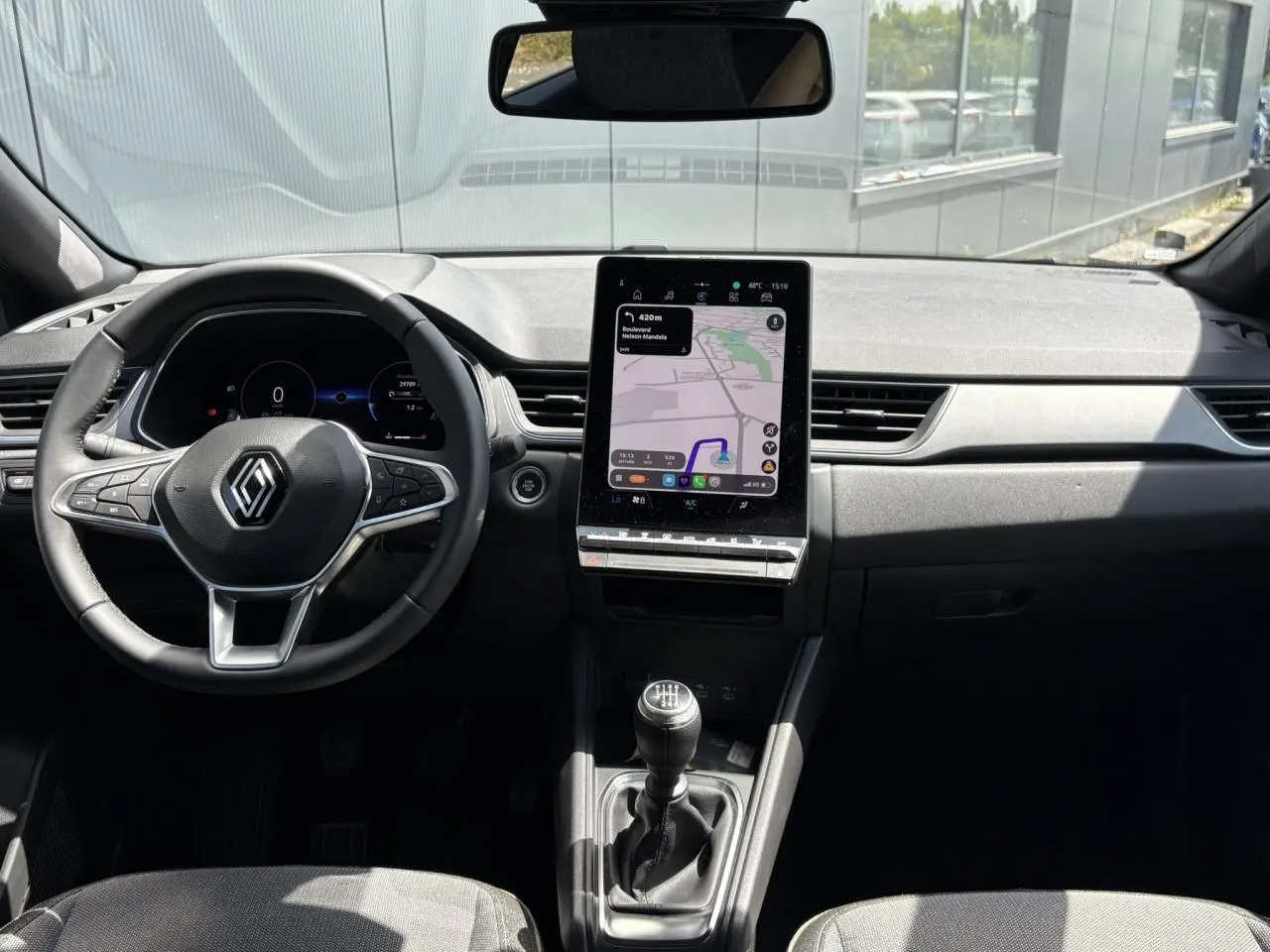 Vue intérieure avant du Renault Captur TCE 90 Techno 2025, tableau de bord avec écran GPS vertical et volant multifonction.
