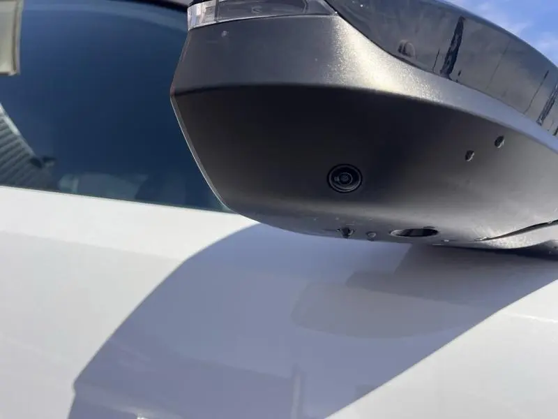 Gros plan sur le rétroviseur côté droit blanc Okénite du Peugeot 5008 Hybrid 145ch Allure e-DCS6 avec caméra intégrée.