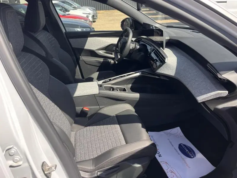 Vue intérieure côté conducteur du Peugeot 5008 Hybrid blanc, avec sièges tissu gris et tableau de bord moderne.