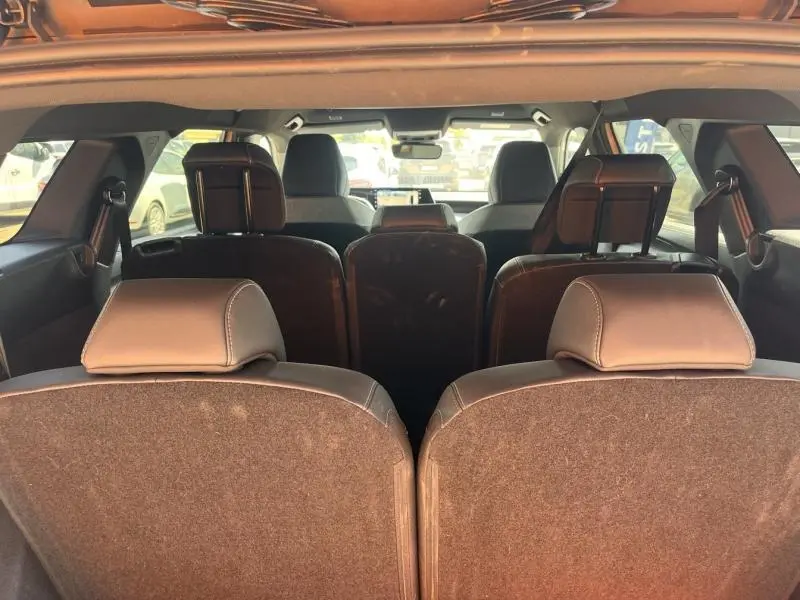 Vue arrière intérieure du Peugeot 5008 Hybrid blanc, montrant les trois rangées de sièges avec appuis-tête en cuir.