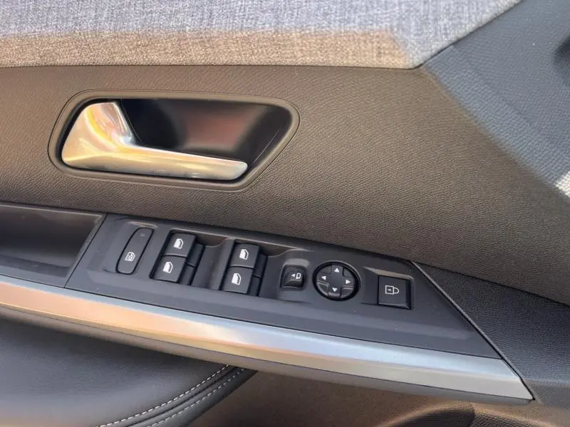 Gros plan sur la commande des vitres et la poignée intérieure côté gauche du Peugeot 5008 blanc Okénite.