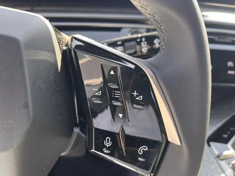 Gros plan sur les commandes tactiles noires du volant cuir du Peugeot 5008 blanc Okénite, côté gauche.