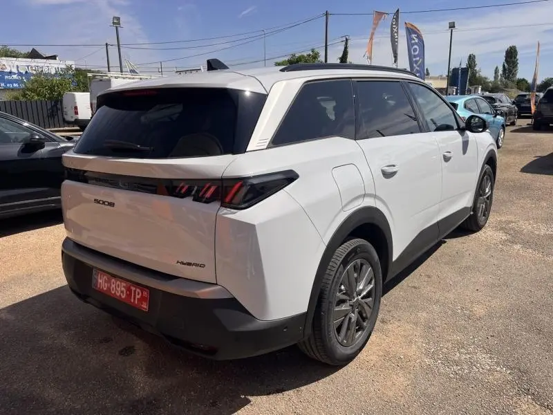 Vue 3/4 arrière droite du Peugeot 5008 Hybrid blanc Okénite avec vitres arrière surteintées et jantes alu.