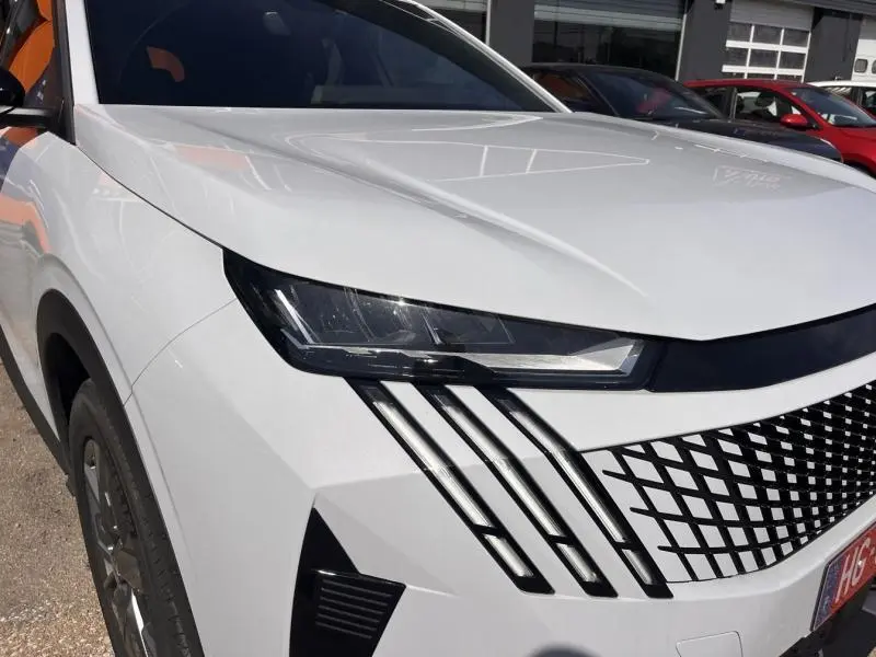 Vue avant gauche du Peugeot 5008 Hybrid blanc Okénite avec phares LED et signature lumineuse verticale distinctive.