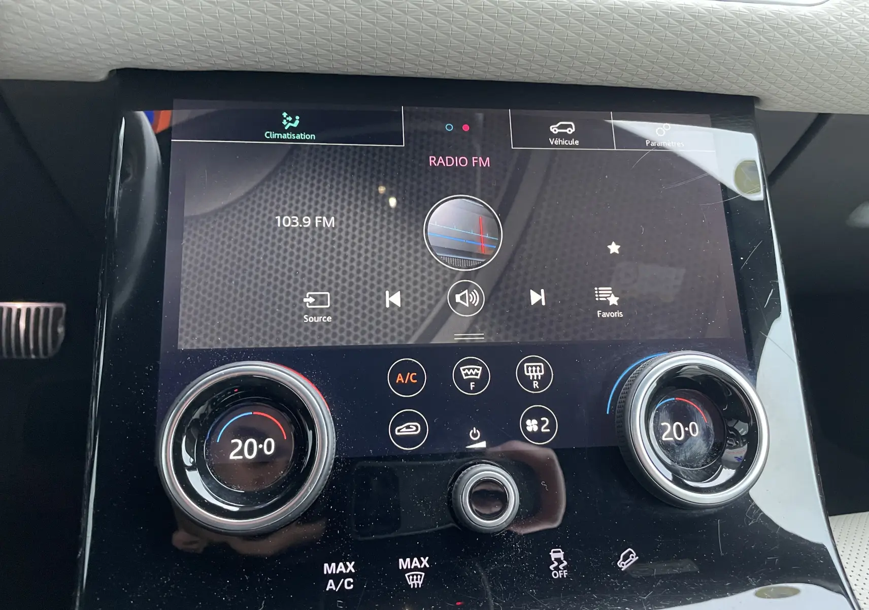 Gros plan sur l'écran tactile central et les commandes de climatisation du Range Rover Velar D300 2018 en intérieur noir et beige.