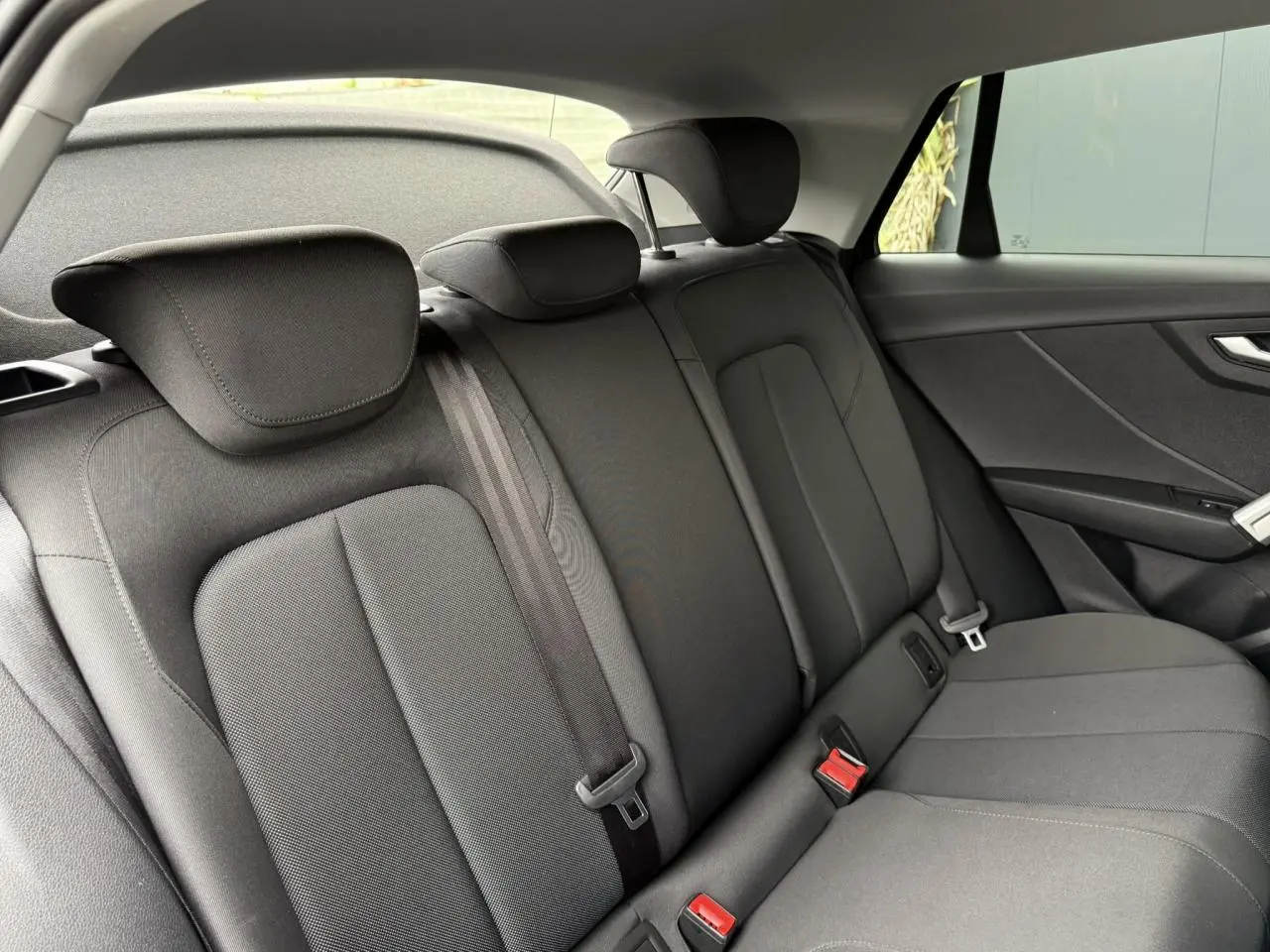Vue intérieure des sièges arrière noirs de l'Audi Q2 35 TFSI S-Line, mettant en valeur l'espace et les appuie-têtes.