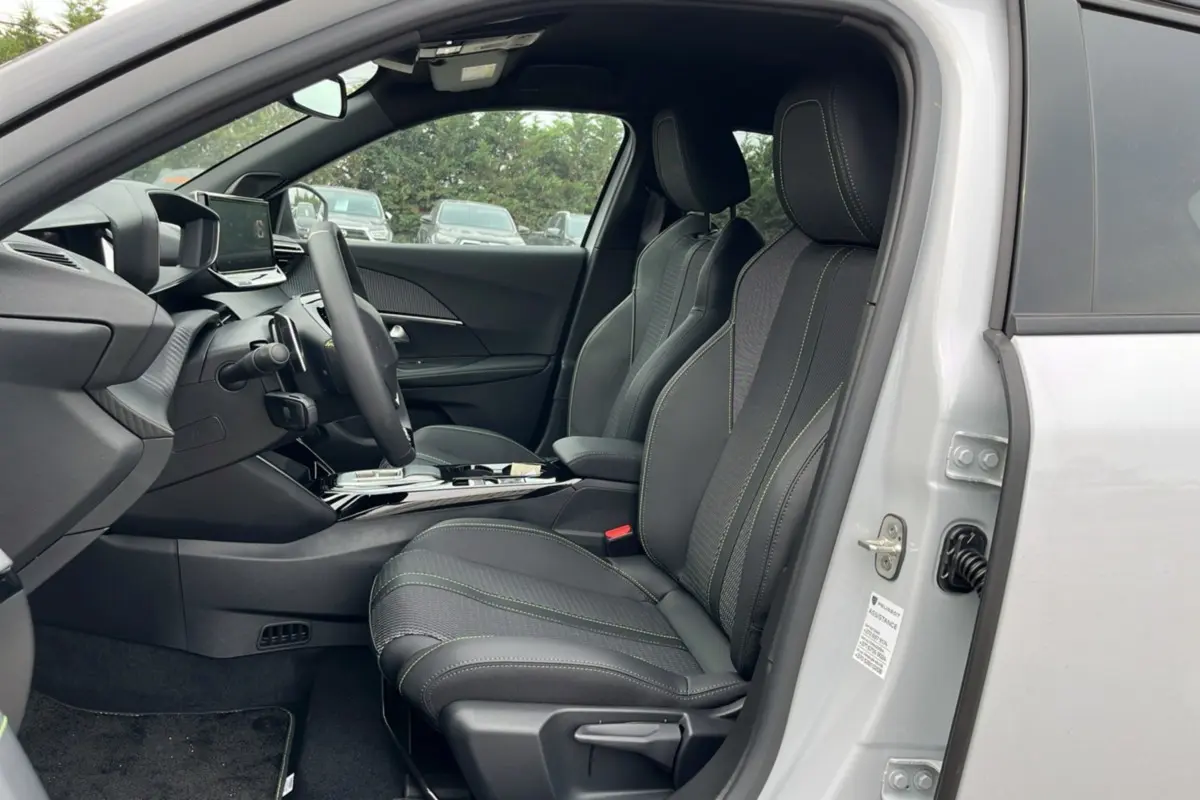 Intérieur côté conducteur du Peugeot 2008 Hybrid 145 GT Vision 2025, sièges noirs avec surpiqûres vertes et tableau de bord moderne.