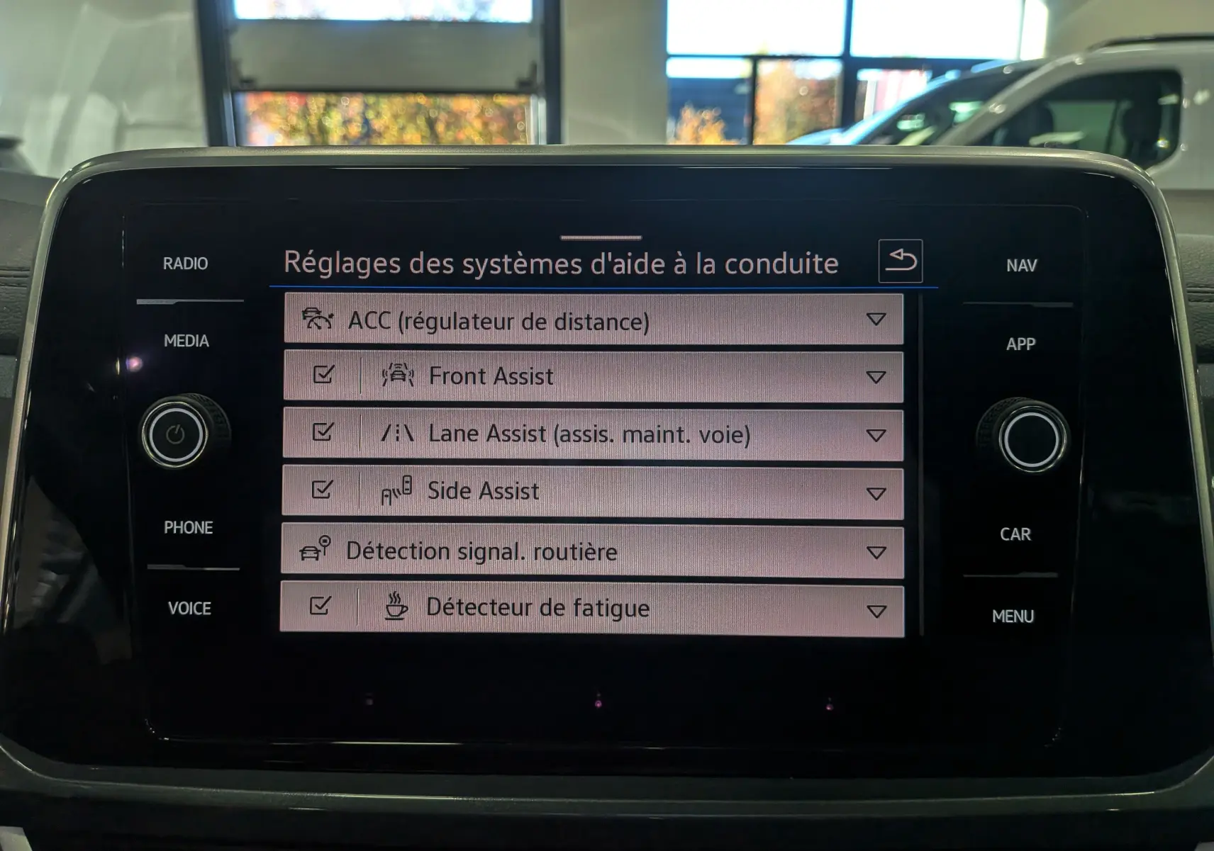Écran tactile central du Volkswagen T-Roc 2024 affichant les réglages des aides à la conduite en intérieur.