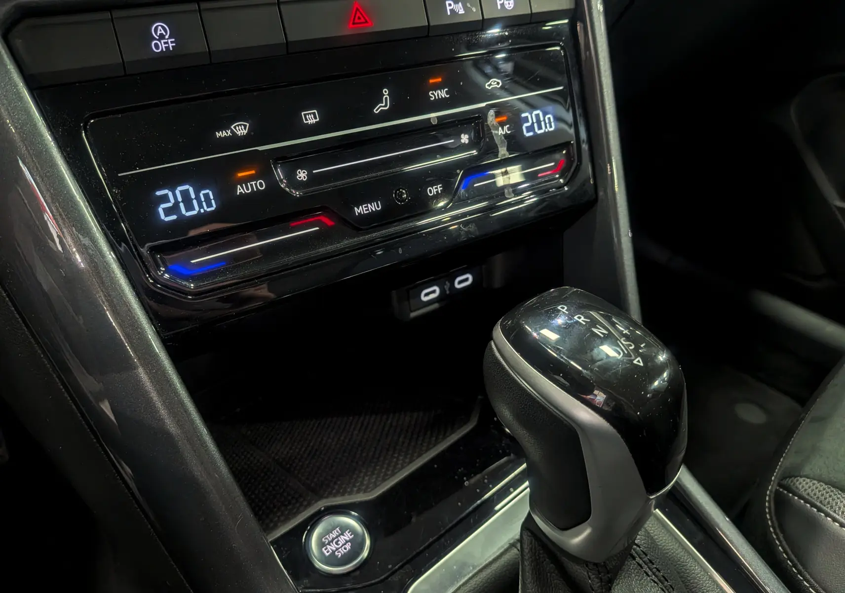 Gros plan sur la console centrale du Volkswagen T-Roc gris pyrite 2024, avec levier de vitesses automatique et commandes climatisation digitale.