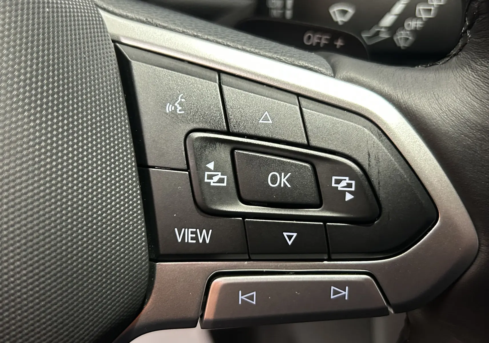 Gros plan sur les commandes multifonctions noires et argent du volant du Volkswagen T-Roc TSI 150 DSG Life 2025.