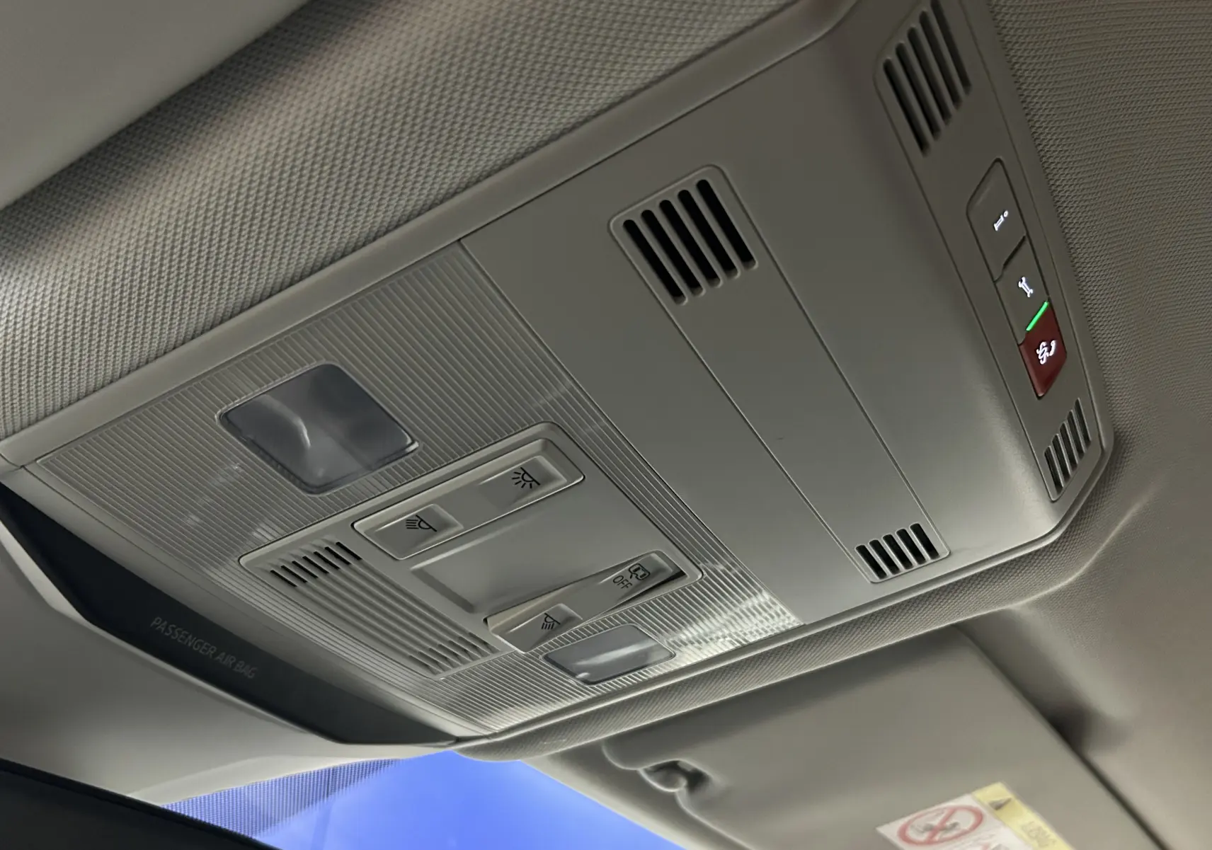 Plafonnier intérieur gris clair du Volkswagen T-Roc 2025 avec commandes d’éclairage et ventilation, vue en légère contre-plongée.
