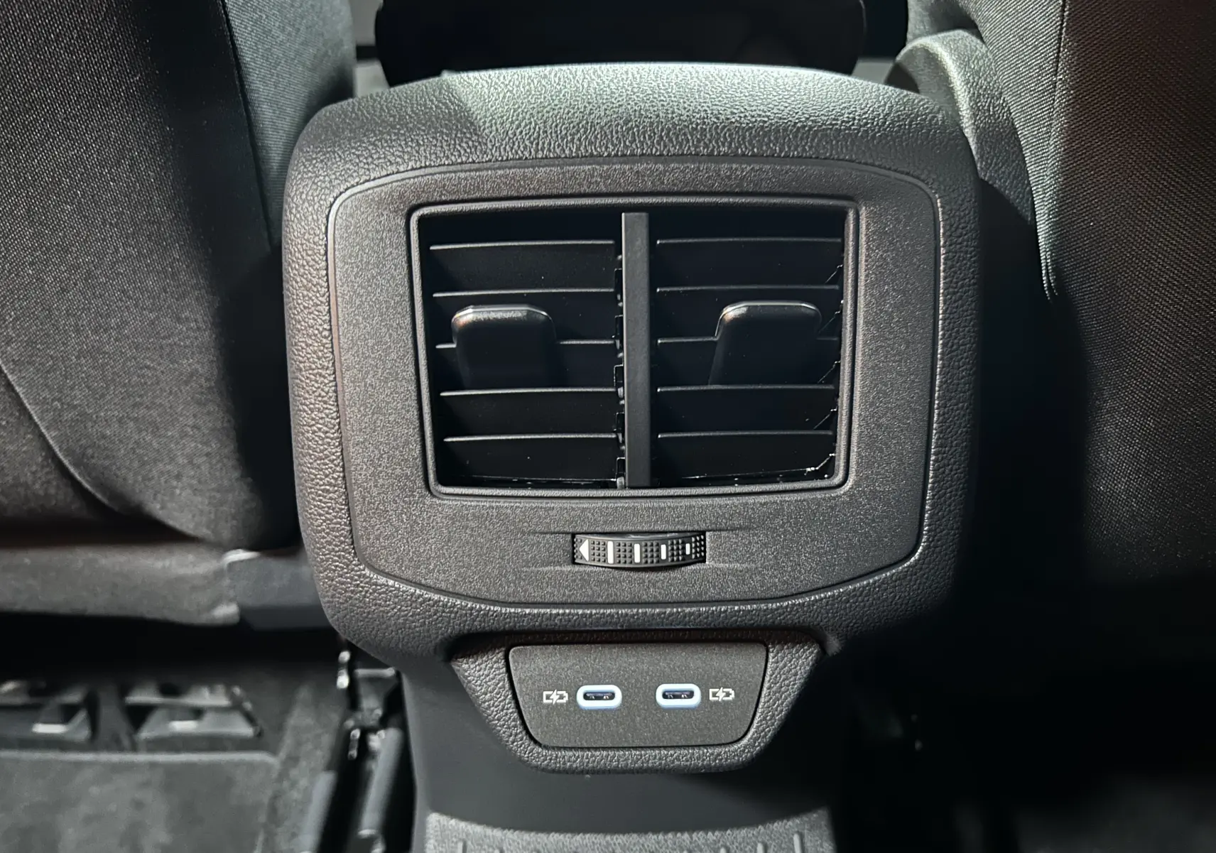 Gros plan sur la console arrière noire du Volkswagen T-Roc 2025 avec bouches d’aération et deux ports USB-C.