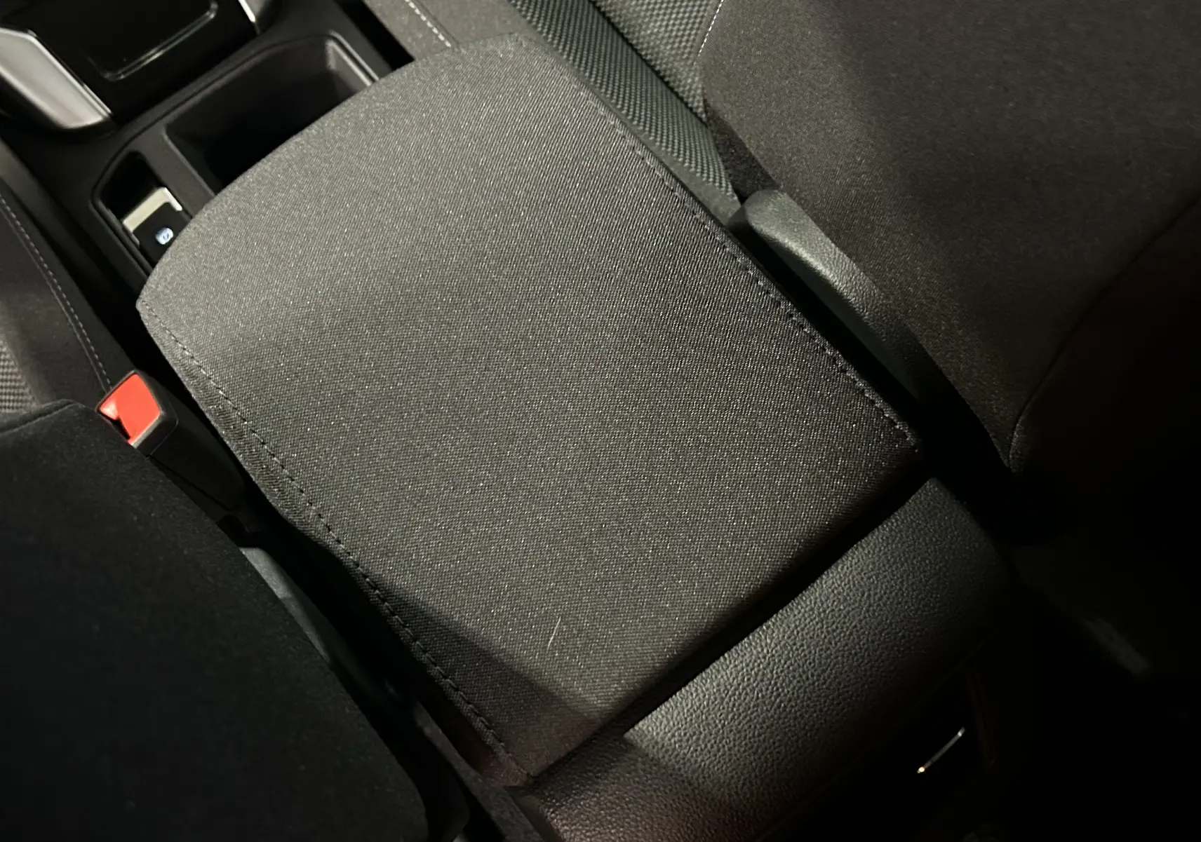 Gros plan sur l'accoudoir central en tissu noir de l'intérieur du Volkswagen T-Roc TSI 150 DSG Life 30 Years.