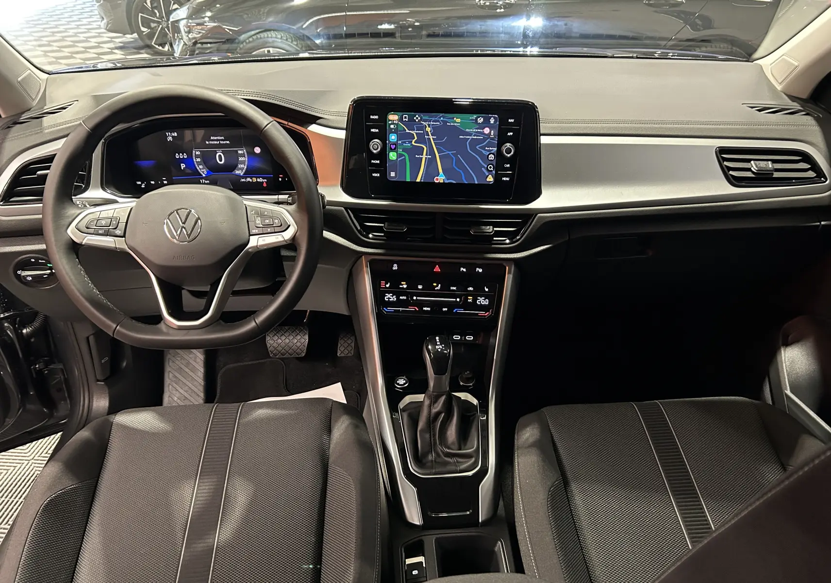 Vue intérieure du tableau de bord du Volkswagen T-Roc 2025, avec écran tactile central affichant la navigation.