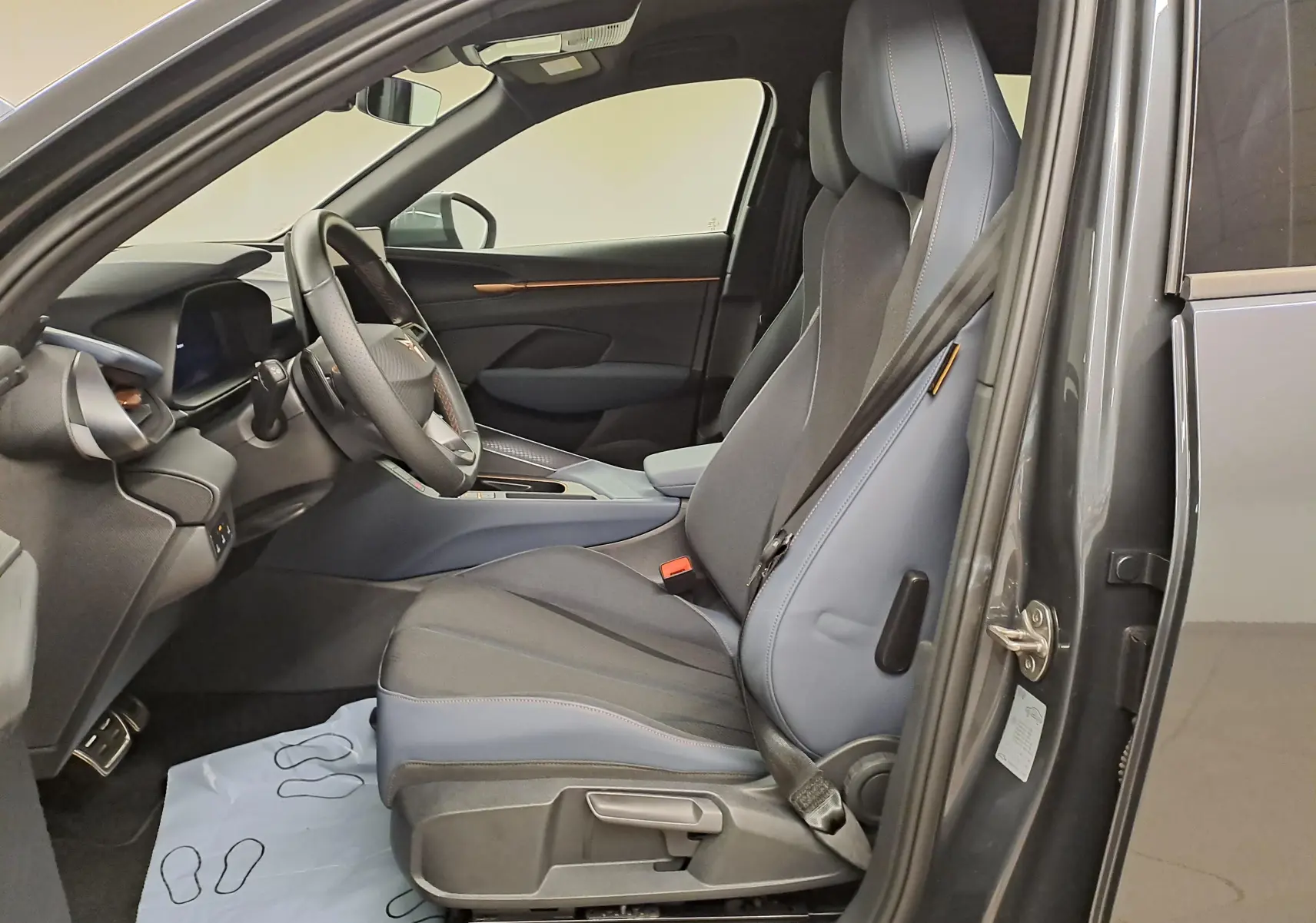 Vue intérieure côté conducteur de la CUPRA TERRAMAR 2025 en Gris Timanfaya, sièges sport et tableau de bord moderne.