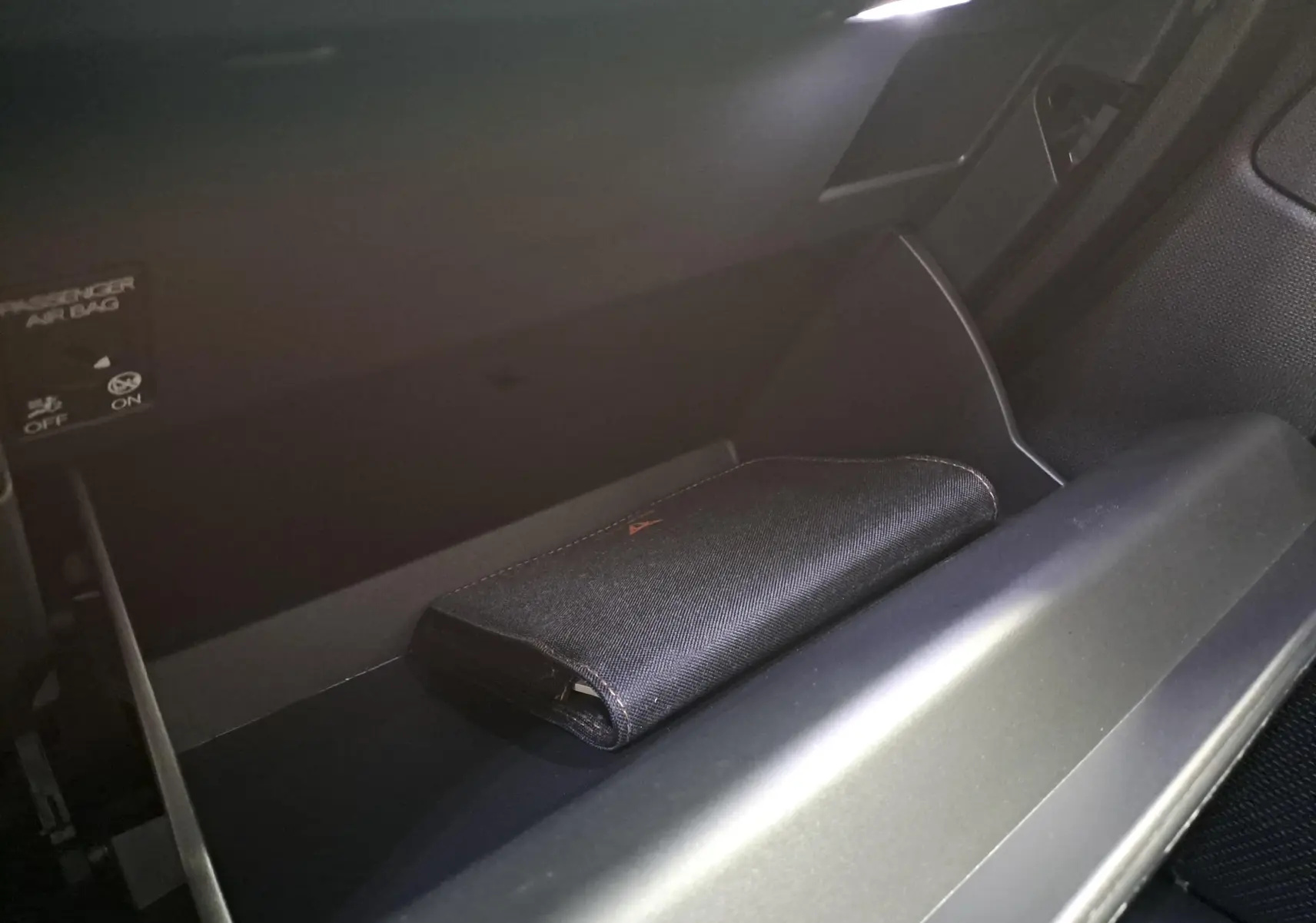 Gant de boîte à gants ouvert avec pochette noire siglée CUPRA à l'intérieur, intérieur avant droit du véhicule.